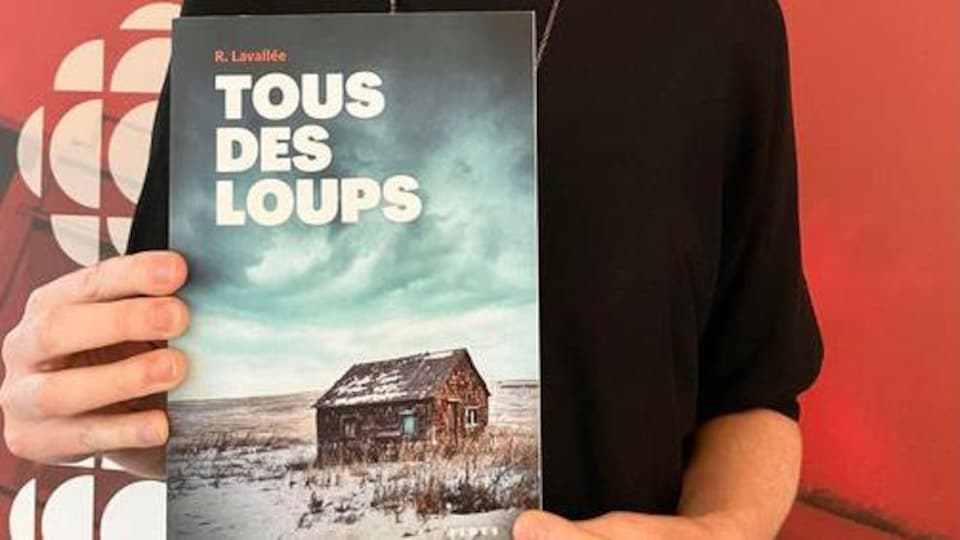 La couverture du roman de Ronald Lavallée 'Tous des loups' entre les mains de Mireille Langlois, animatrice de Culture et Confiture.