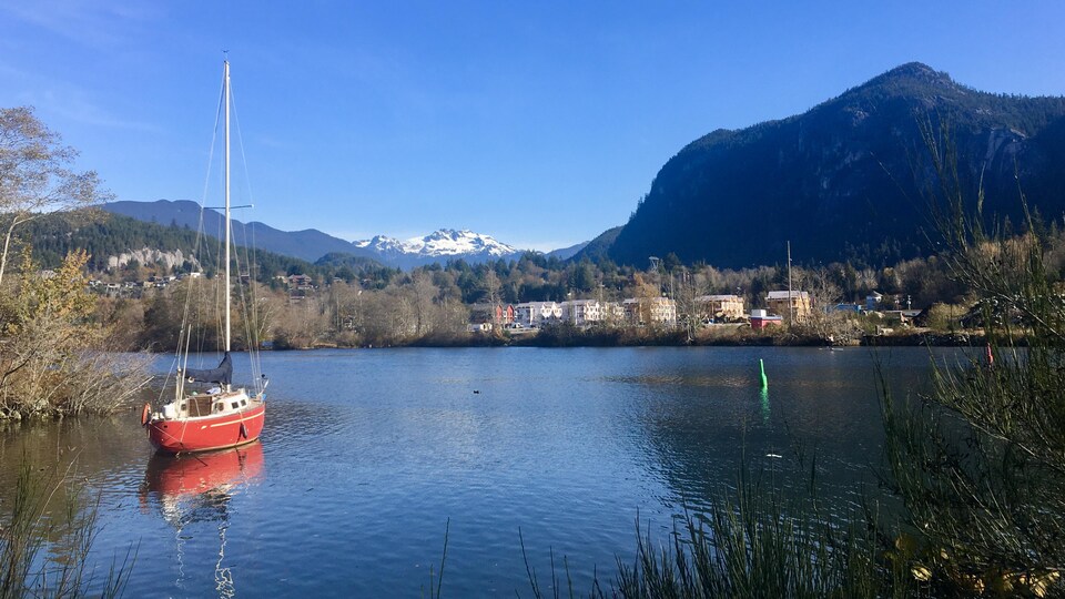 Un voilier sur l'eau avec en arrière plan les montagnes.