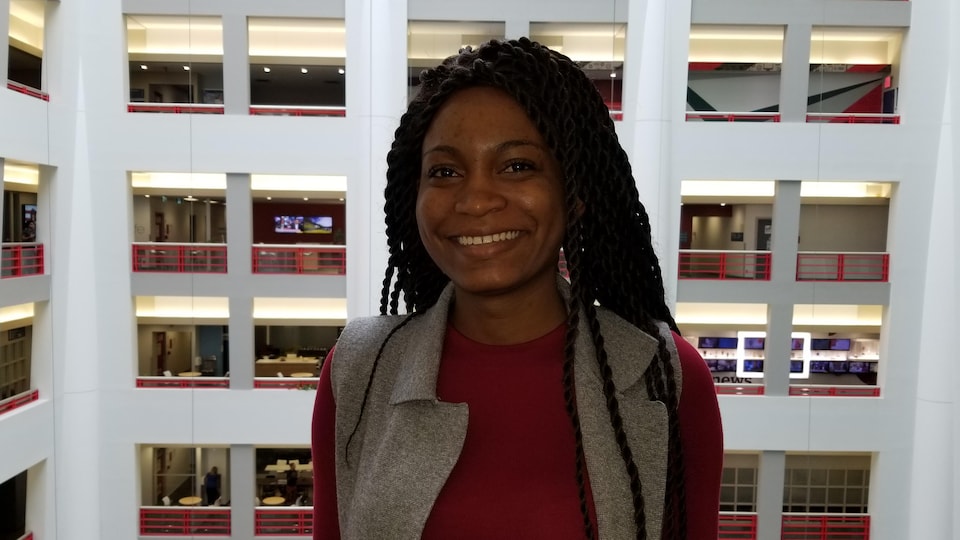 Céleste Tshizena se tient devant l'atrium de Radio-Canada.