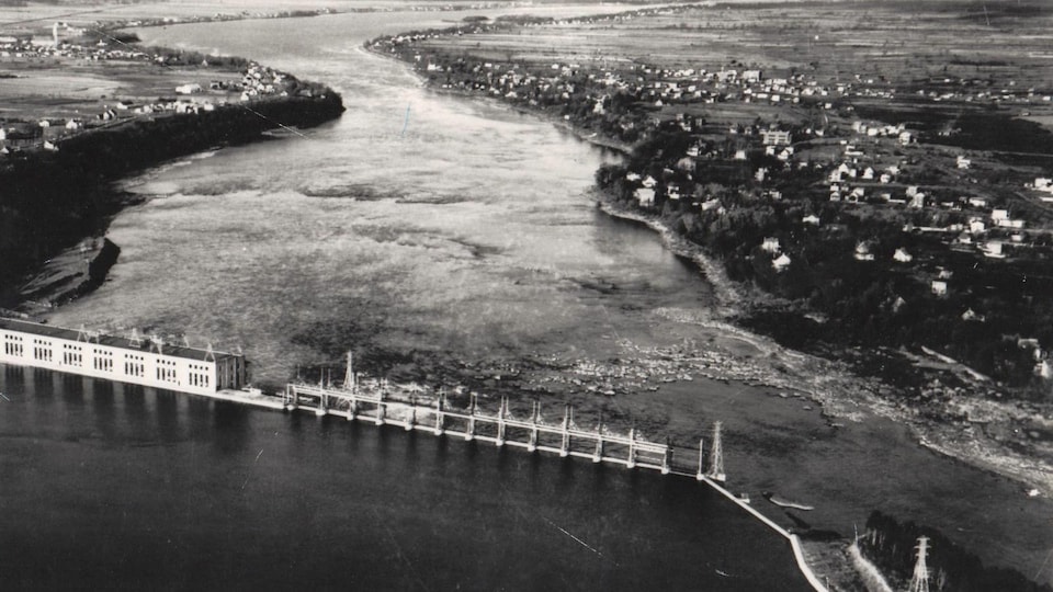 Photo en noir et blanc d'une vue aérienne d'une centrale hydroélectrique sur une rivière.