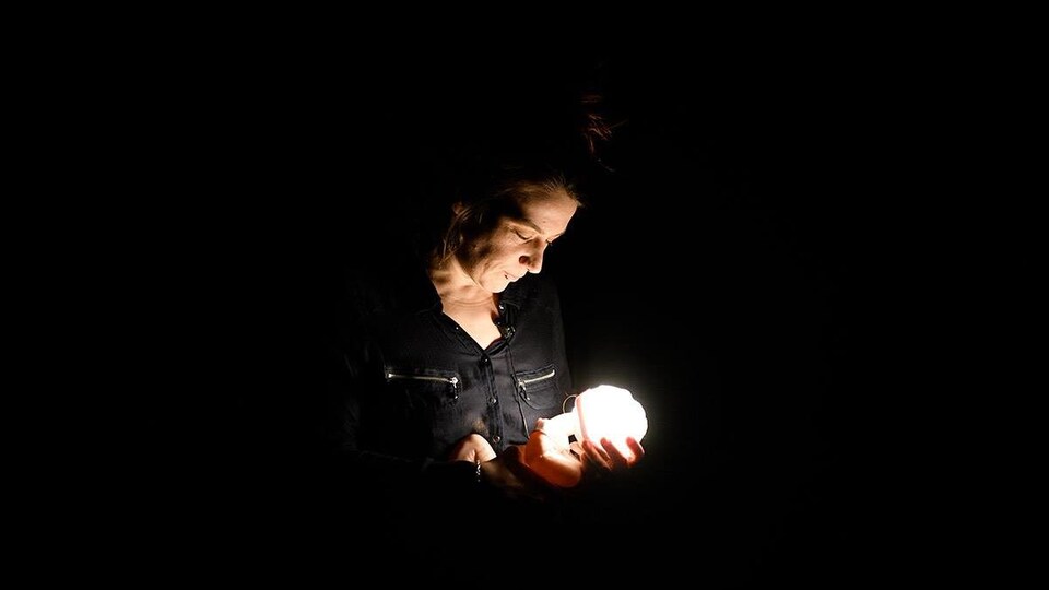 Une femme tient une poupée qui s'illumine.