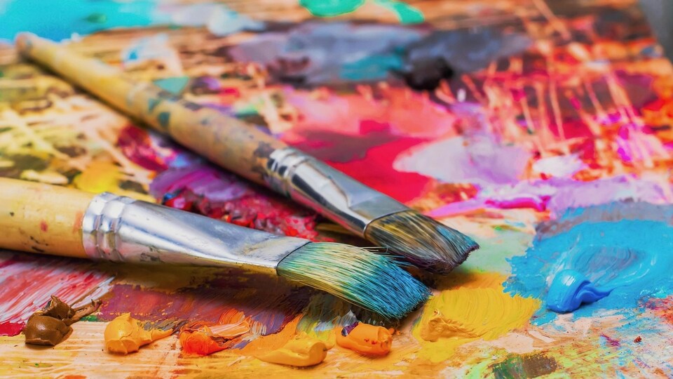 Des pinceaux se trouvent sur la palette d'un artiste.