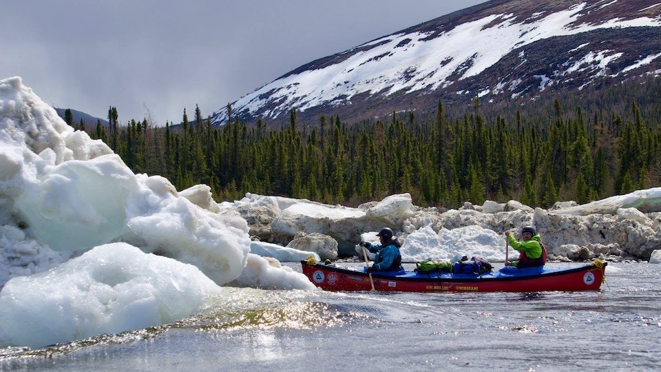 Deux jeunes dans un canot contournent les glaces d'une rivière du Grand Nord.