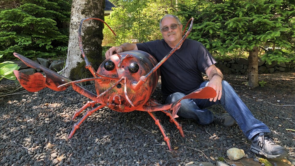 Un homme et une sculpture d'un homard en fer.