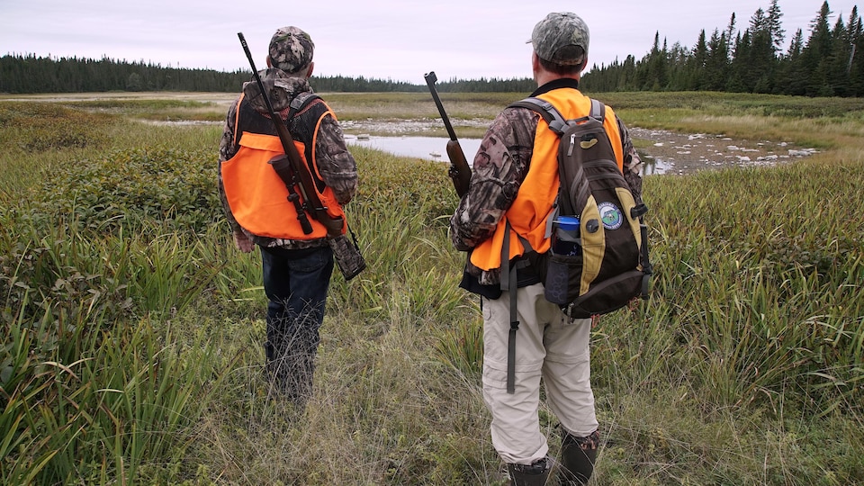 Deux chasseurs guettent l'horizon dans une clairière.