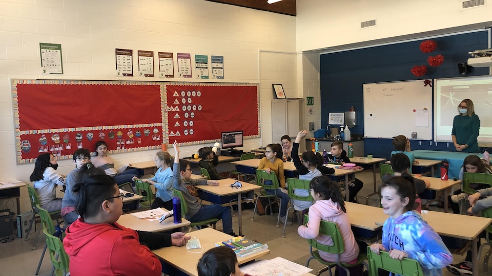 L'enseignante Christelle Lebel et ses élèves assis devant leur bureau, dans la classe.