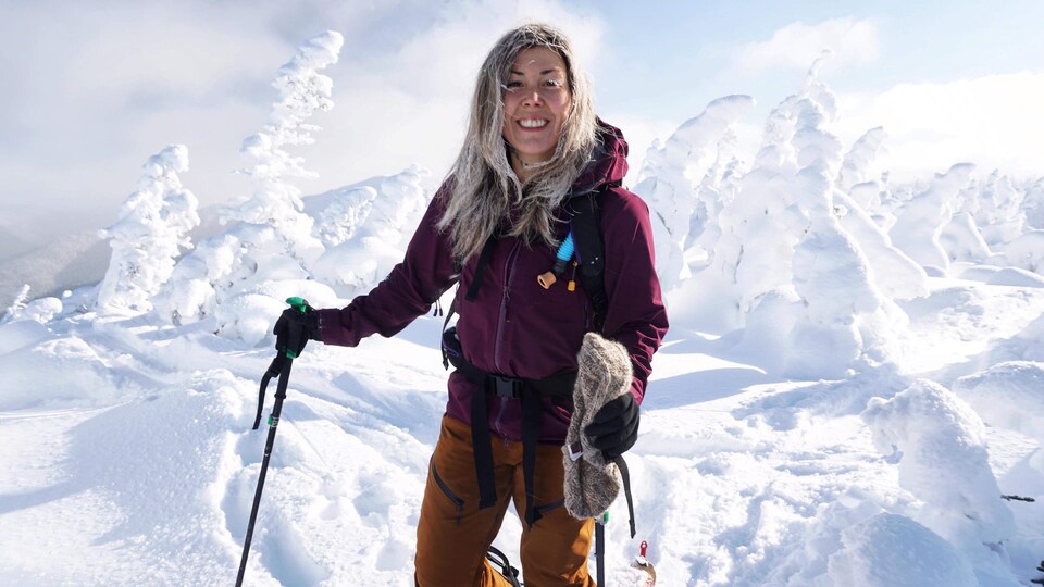 Christine-Bérubé Martin est photographie devant un paysage enneigé avec son équipement de planche à neige