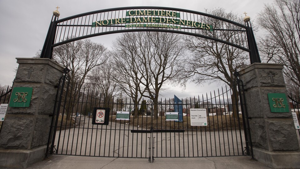 L'entrée d'un cimetière fermée par une grille métallique.