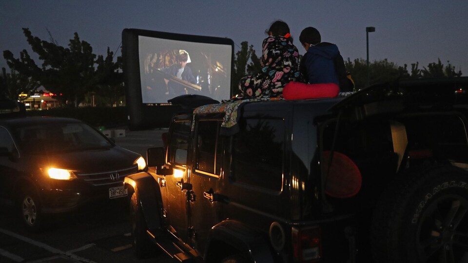 Deux amateurs de cinéma regardent un film sur leur toit de leur camion.