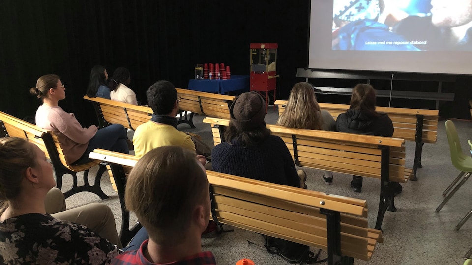 Des personnes assises devant un écran de cinéma.