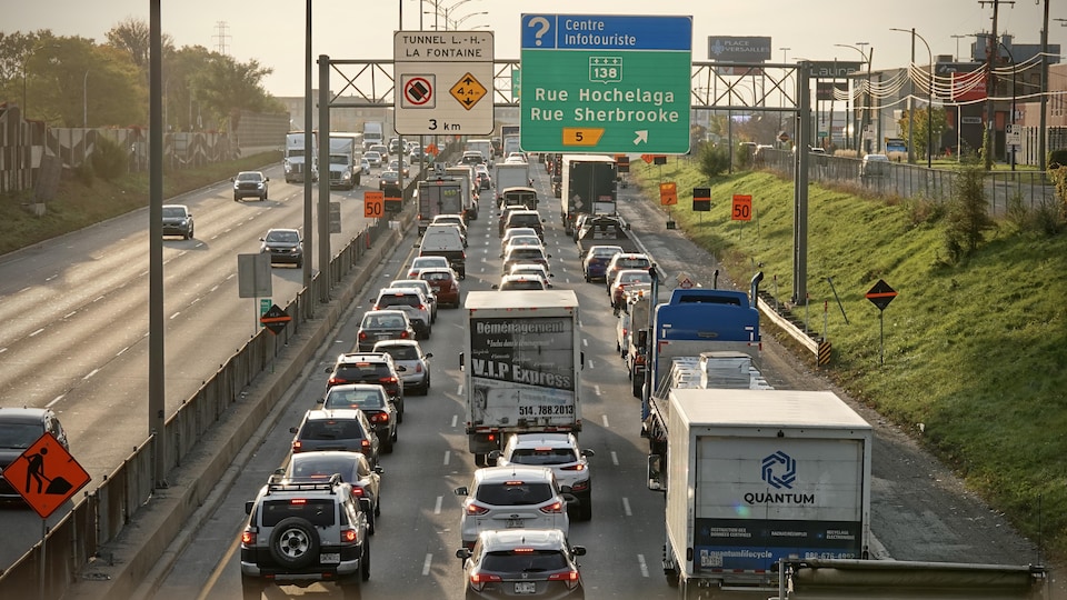 Des voitures et des camions roulent pare-choc contre pare-choc sur une autoroute.