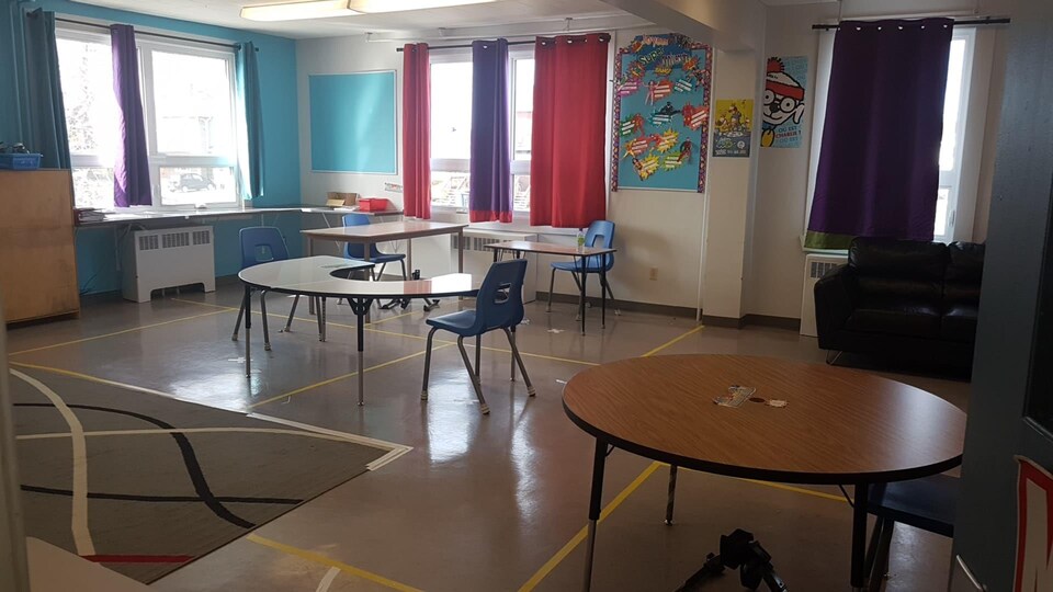 Une classe du primaire avec des tables et des chaises distanciés de 2 mètres.
