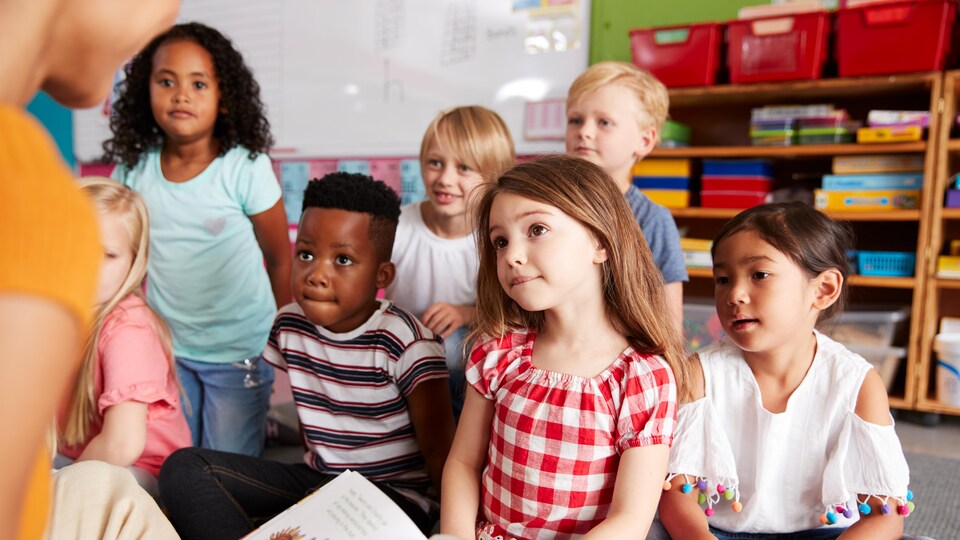 Une enseignante lit une histoire à de petits élèves.