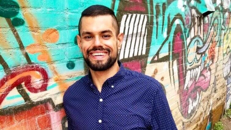 Kevin Prada devant un mur de graffitis.