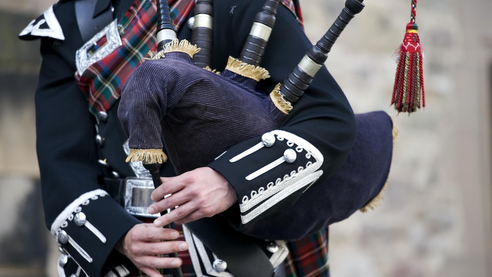 Gros plan sur les mains d'un joueur de cornemuse écossais vêtu d'un tartan écossais traditionnel. 