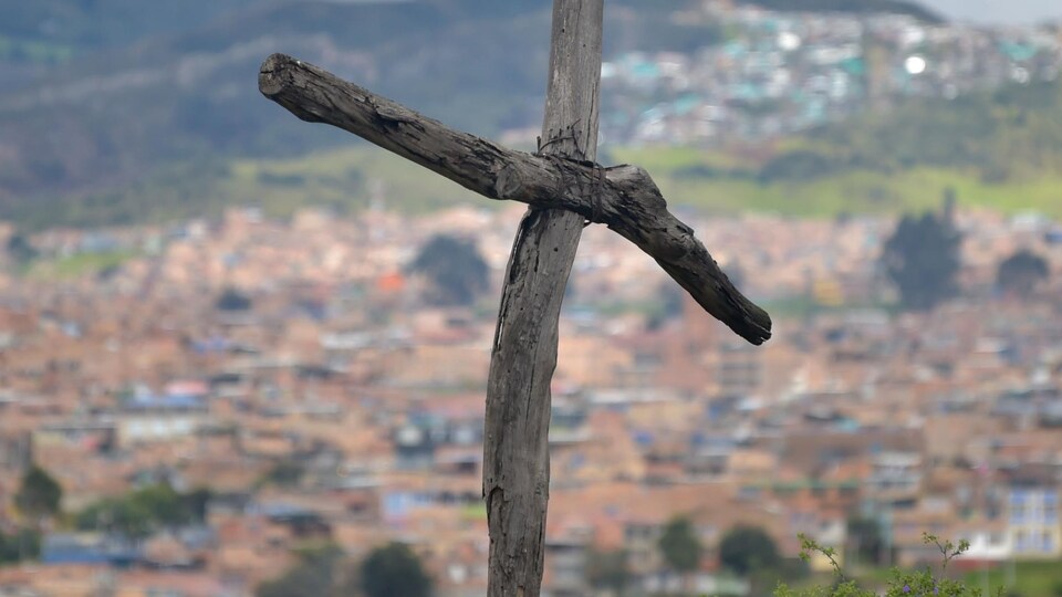 Une croix en bois en avant-plan et la ville au fond.