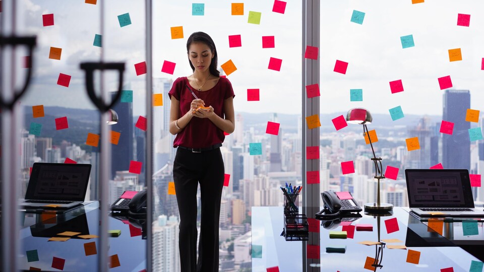 Une femme d'affaires occupée colle de nombreux papillons adhésifs sur les murs de son bureau.
 
