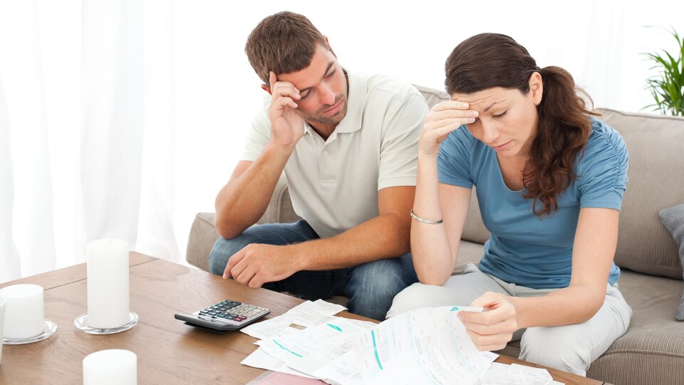 Un couple inquiet consulte des factures.