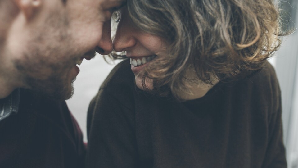 Un homme et une femme se regardent en souriant et en collant leur front l'un sur l'autre.