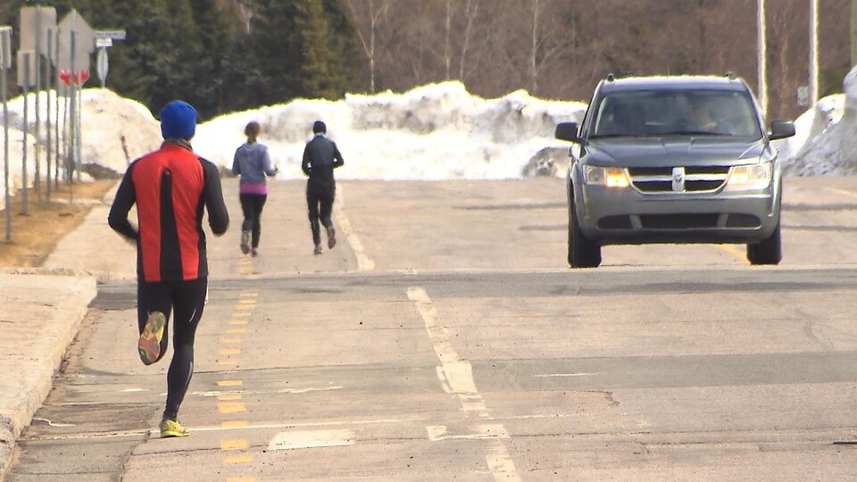 Des gens font leur jogging dans la rue.