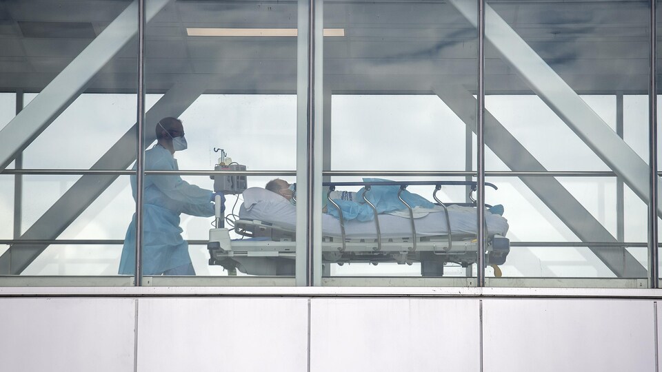 Un infirmier pousse une civière sur laquelle se trouve un patient.