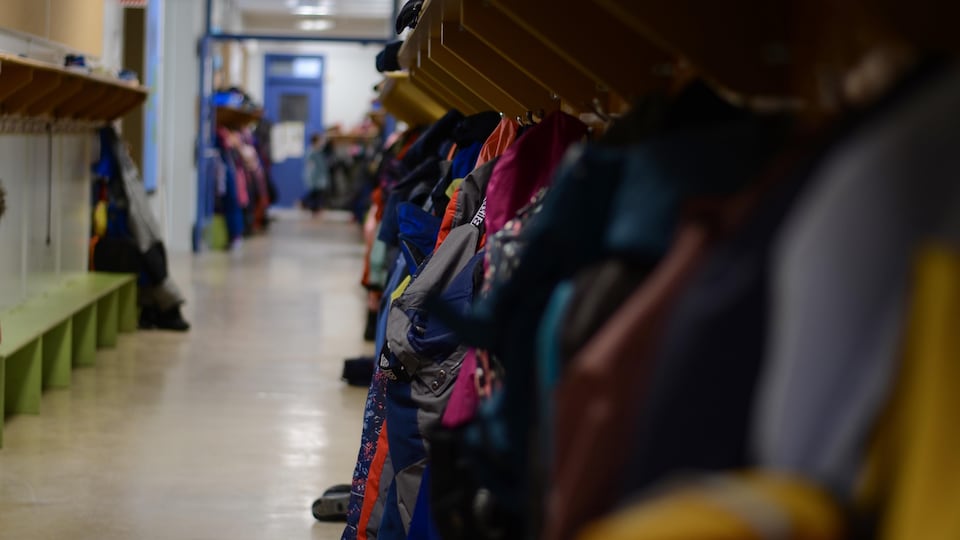 Corridor de l'école primaire où des manteaux sont accrochés aux crochets des casiers d'élèves.