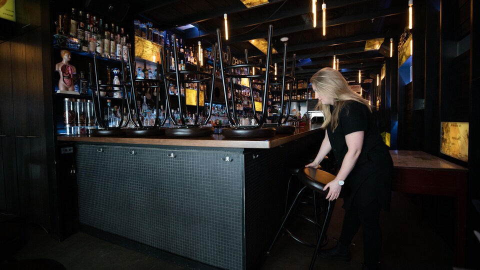 Une femme place les tabourets de son bar sur le comptoir.