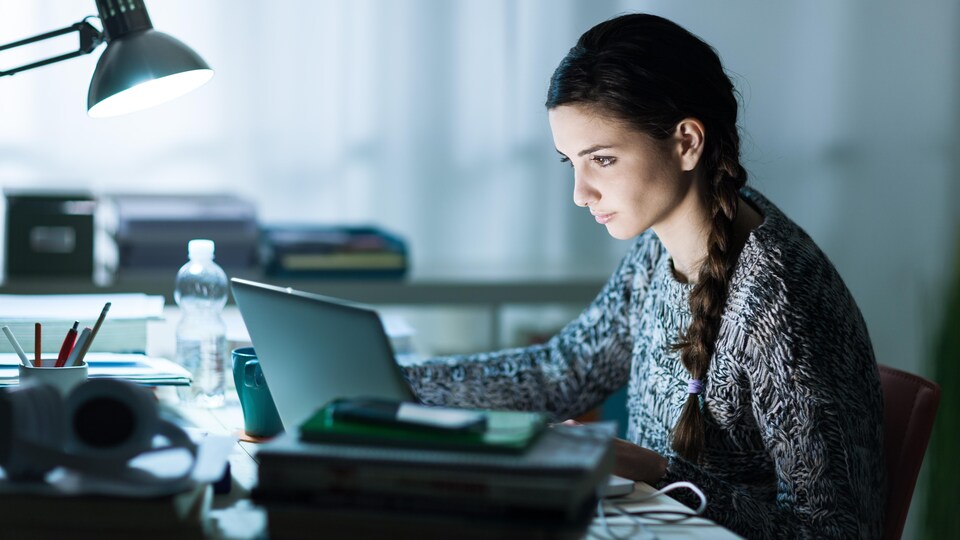 Une jeune femme travaille sur son ordinateur à la maison.