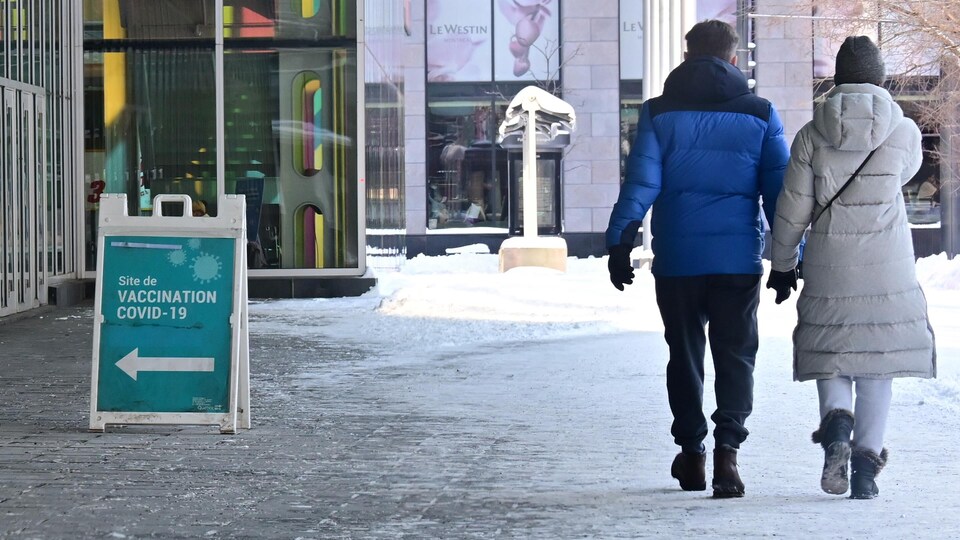 Une couple marchant main dans la main près d'un centre de vaccination contre la COVID-19.