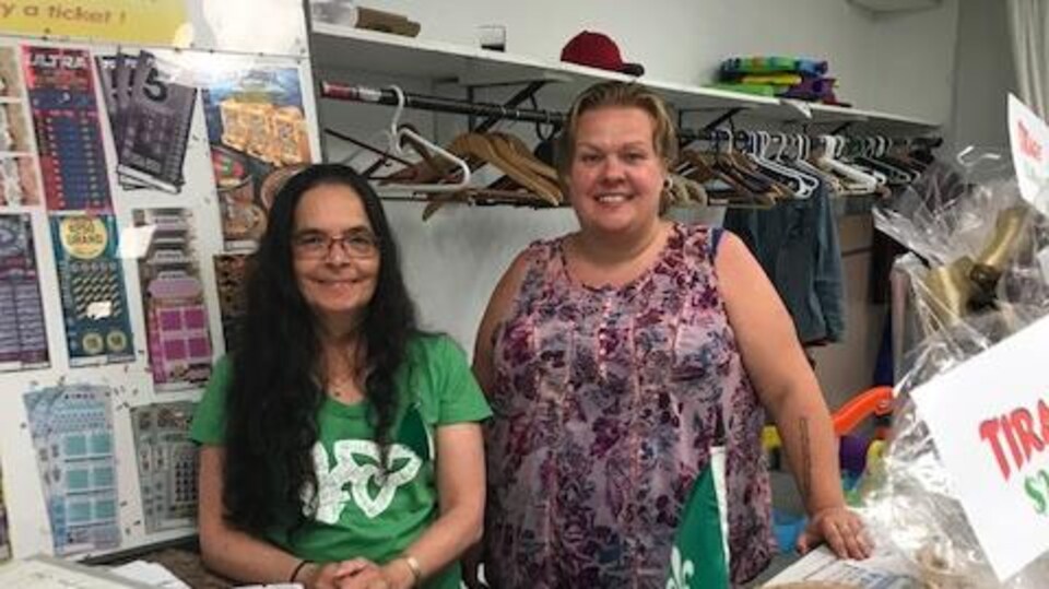 Diane Jean et Monique O'Hearn derrière un comptoir de ventes de billets lors de la fête de la St-Jean du Centre culturel Louis-Hémon
