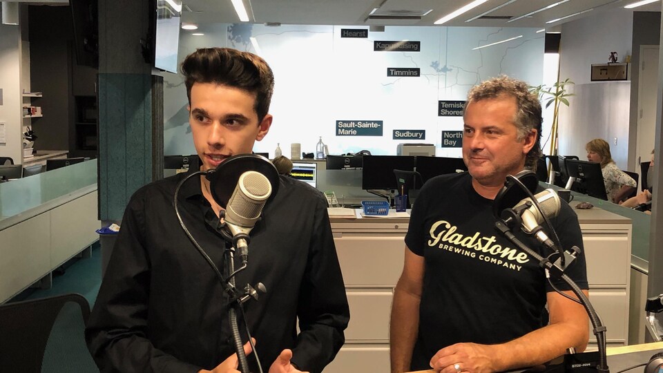 Philippe et André Thériault en studio à Radio-Canada Sudbury. Philippe a un paquet de cartes avec lui.