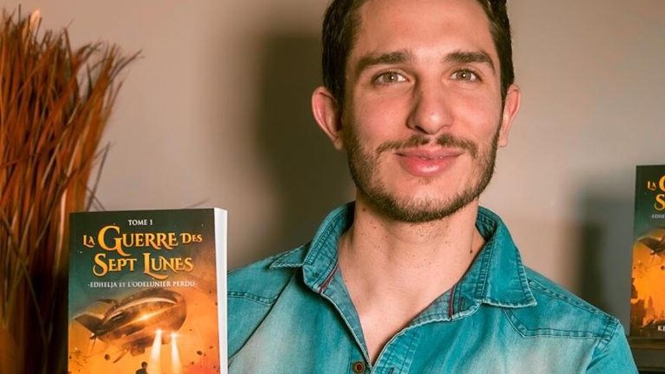 Kenan Olivier tient son roman dans ses mains.