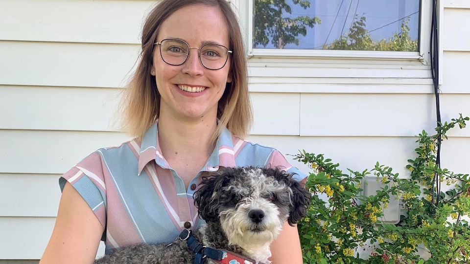 Paula Humby dans sa cour avec un chien dans les bras.