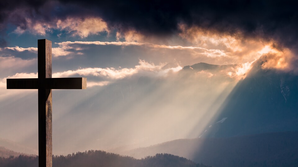 Une croix illuminée par le soleil malgré un ciel nuageux