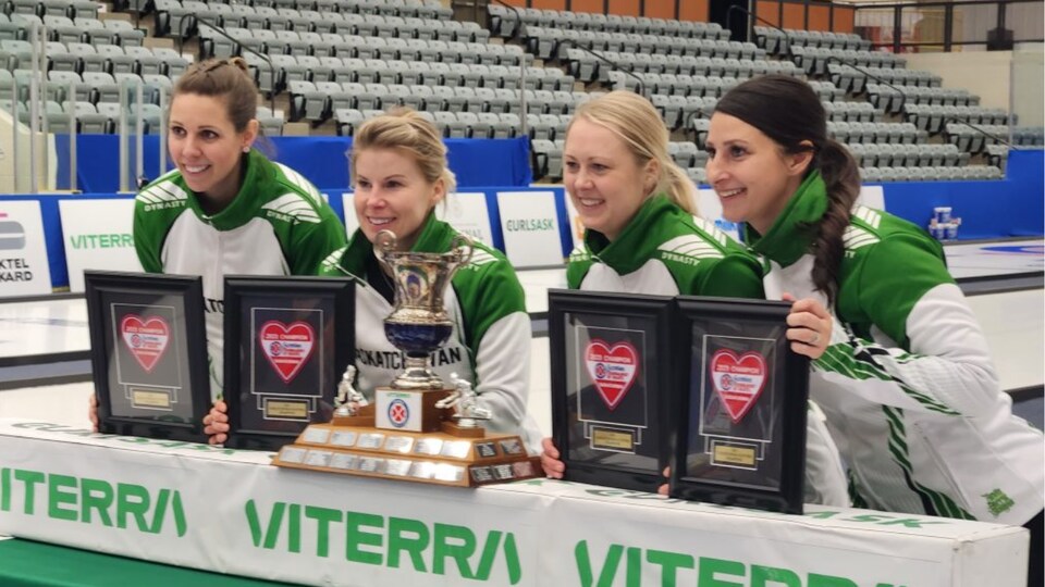 Les quatre membres de l'équipe de curling féminine posent devant leur trophée 