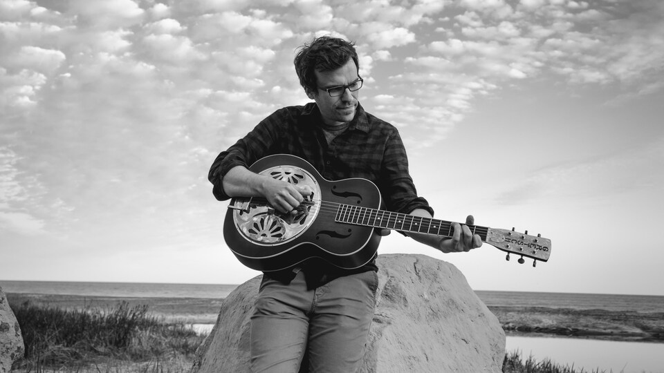 Daniel Otis, auteur-compositeur-interprète nord-côtier, avec sa guitare sur une plage de Sept-Îles