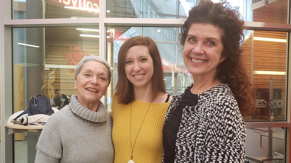 une septuagénaire souriante aux cheveux courts, une trentenaire souriante et animatrice de radio et une grande quinquagénaire souriante se tenants enseble dans le hall de Radio-Canada à Vancouver