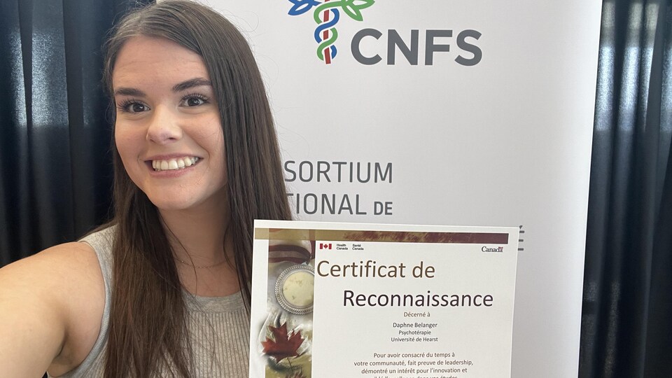 Daphné Bélanger est souriante en tenant un certificat offert par le Consortium National de Formation en Santé.