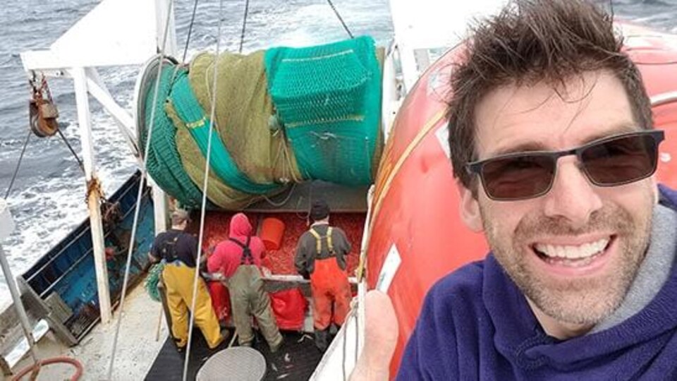 Dave Cotton  sur un bateau avec un équipage derrière lui.