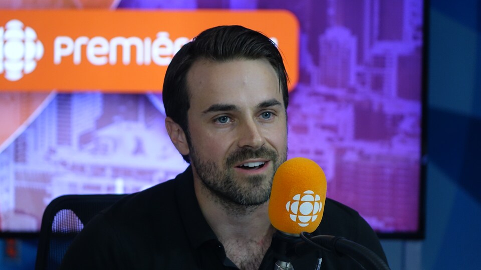 David Laurin derrière un micro dans un studio radio de Radio-Canada.