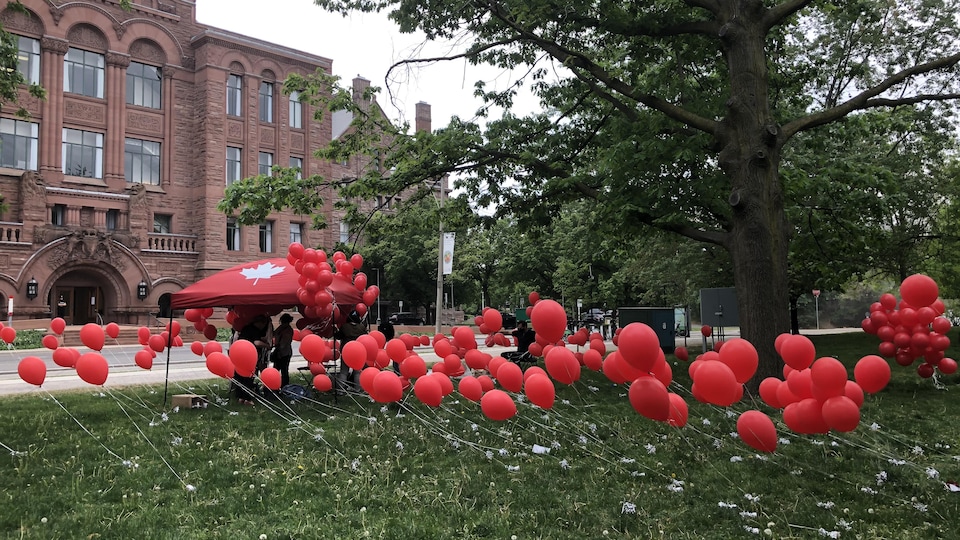 Plusieurs ballons rouges qui flottent devant la législature ontarienne.