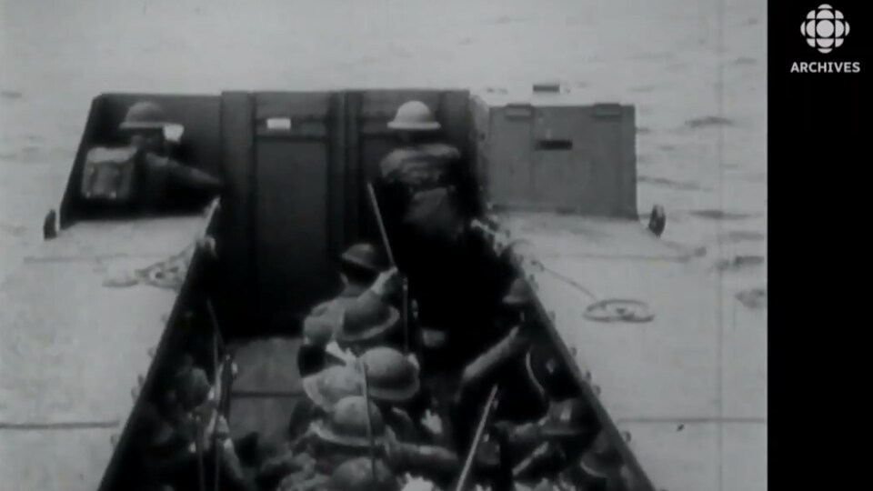 Des soldats dans une péniche s'approchent de la côte normande. 