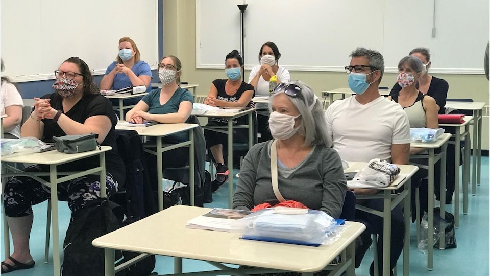 Des aspirants préposés masqués suivent un cours dans une salle de classe.