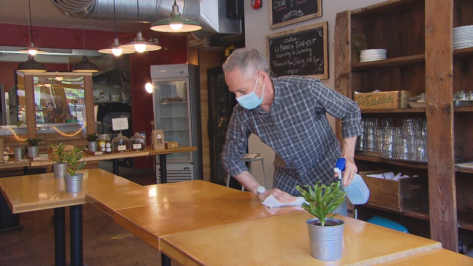 Un homme nettoie une table dans un restaurant.