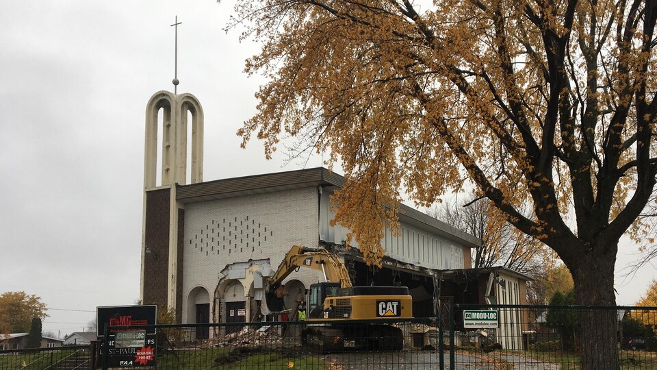 Une pelle mécanique en train de détruire une église à l'architecture moderne.