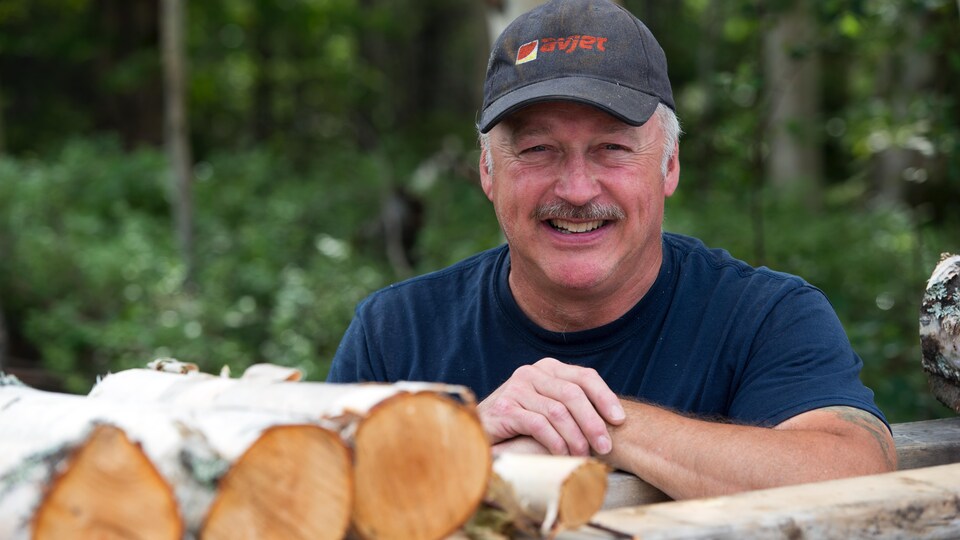 Denis Picard, propriétaire de la bleuetière Bleu Nord à Gallix (dehors, appuyé sur une corde de bois, en saison estivale)