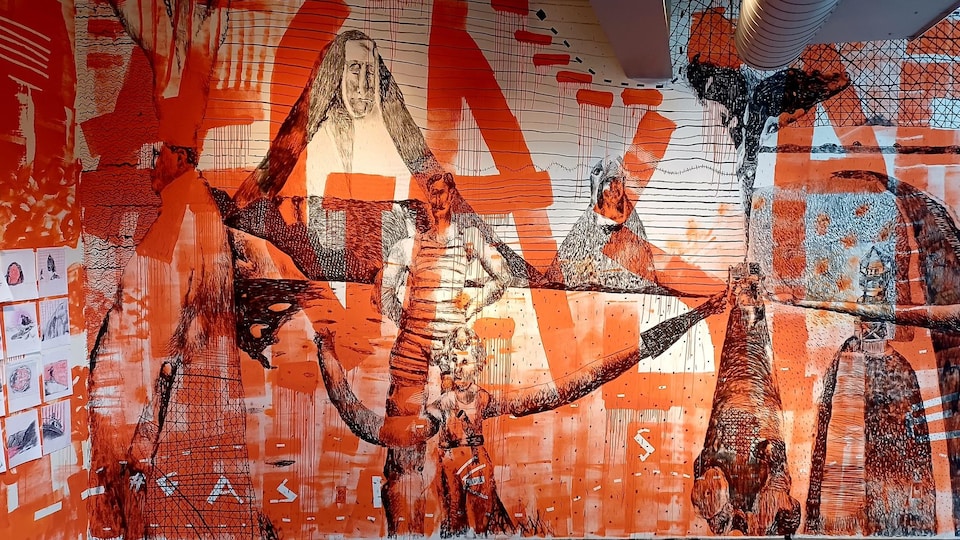 Une œuvre murale fait de dessins au fusain et de coups de pinceau de couleur orange.