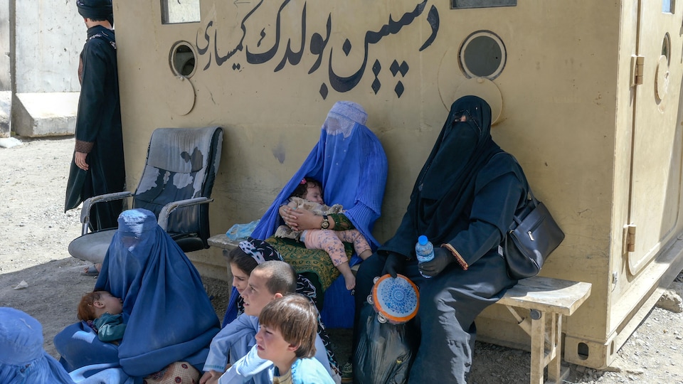 Des femmes en burqa assises avec leurs enfants.