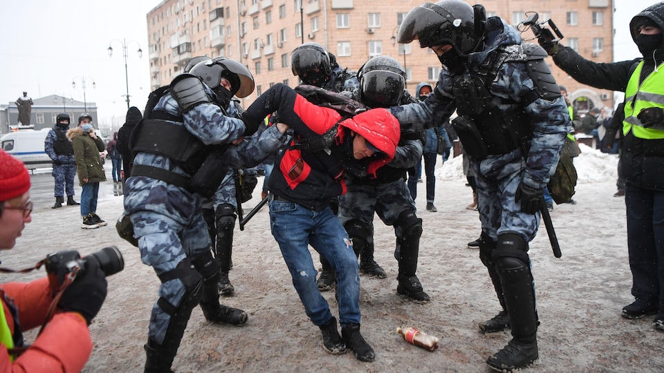 Des policiers antiémeute en Russie procèdent à une arrestation musclée d'un jeune manifestant.