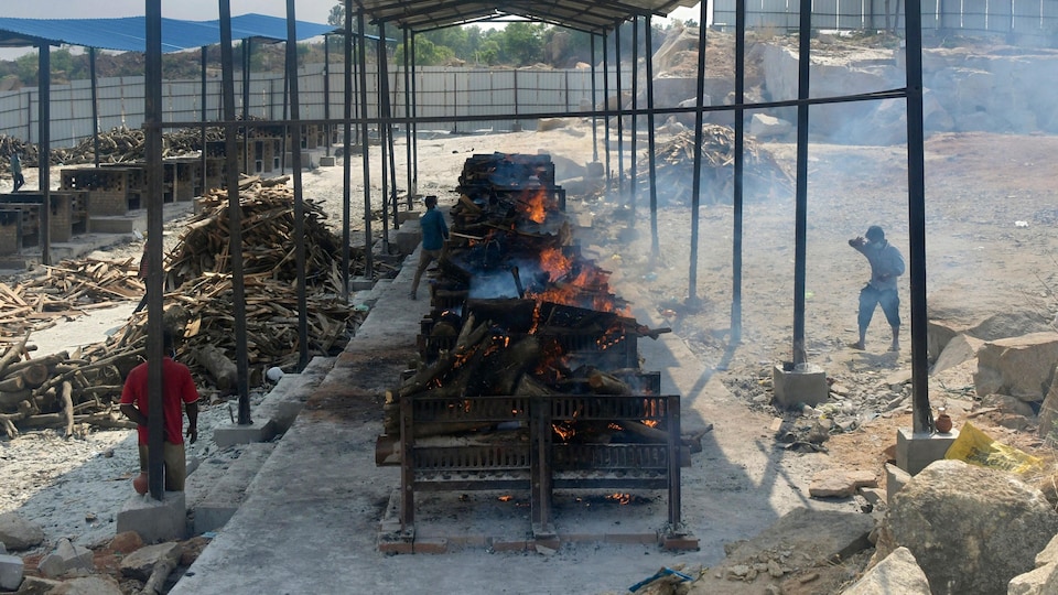 Des bûchers en feu pour les victimes de la COVID-19 dans un crématorium en plein air à l’intérieur d’une ancienne carrière de granit à la périphérie de Bangalore en Inde